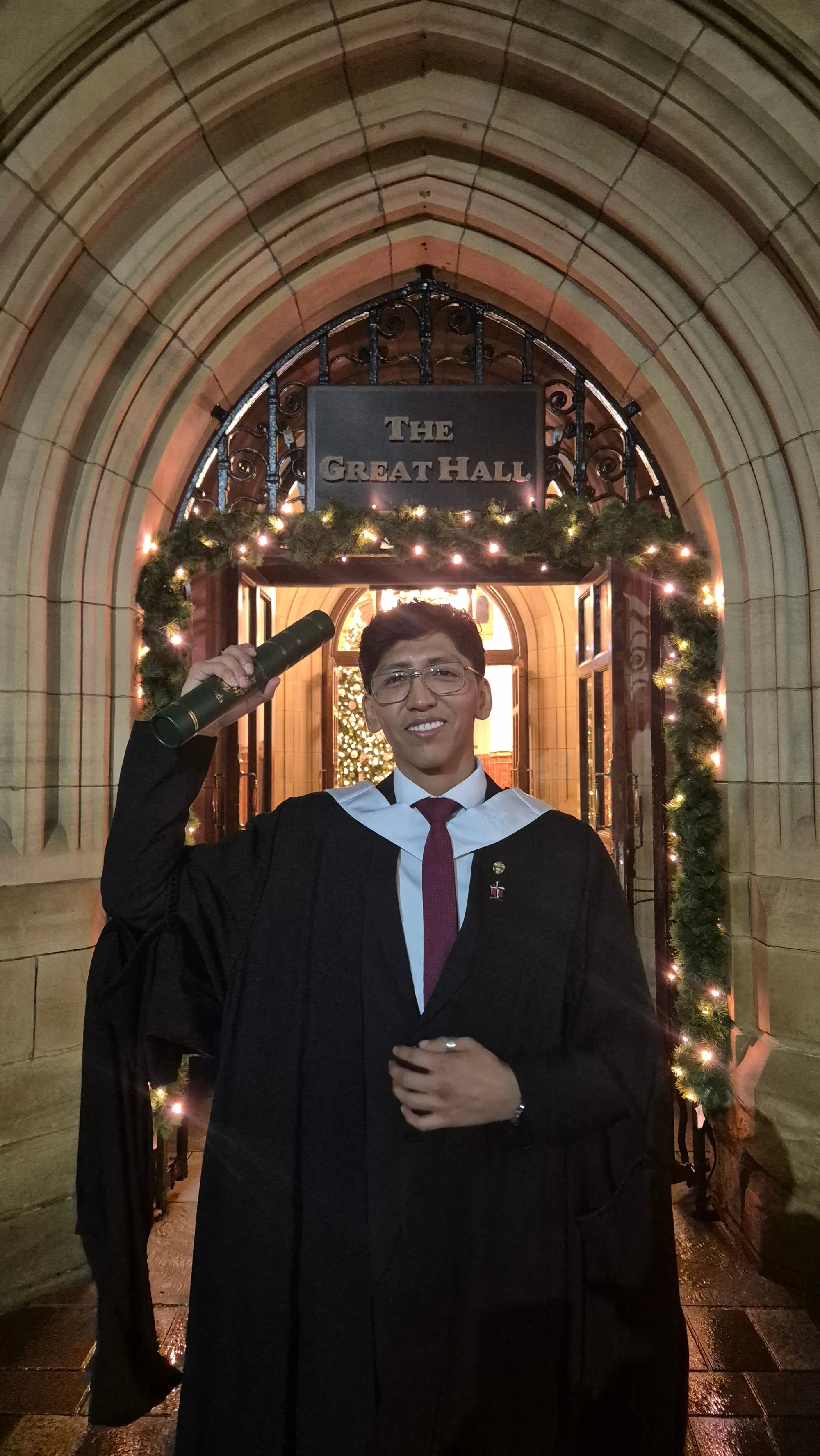 Kenji Hilasaca in graduation robes outside the University of Leeds Great Hall