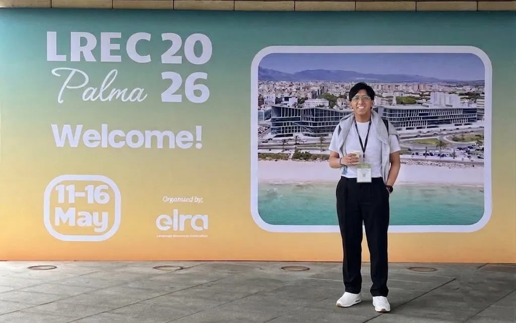 Kenji Hilasaca standing beside the LREC 2026 welcome display in Palma